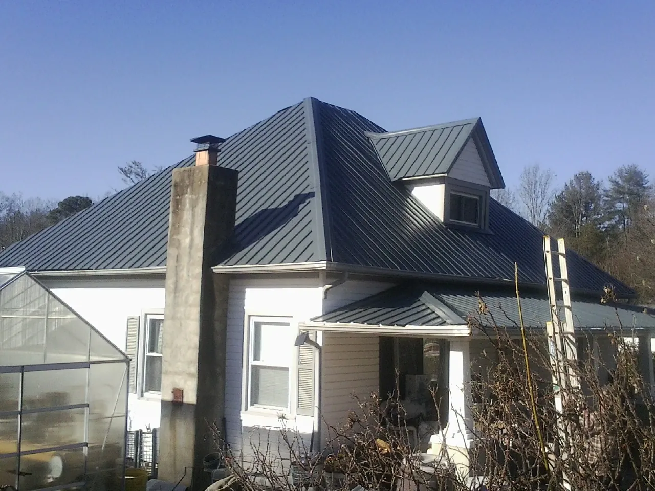 Dark blue standing seam metal roof on a white farmhouse with dormer — Slate & Tile Roof Repair by Roofing Brothers in Kirkersville