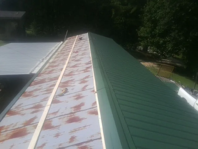Old rusted panels beside newly installed green metal roofing — Wind Damage Roof Repair by Roofing Brothers in Kirkersville