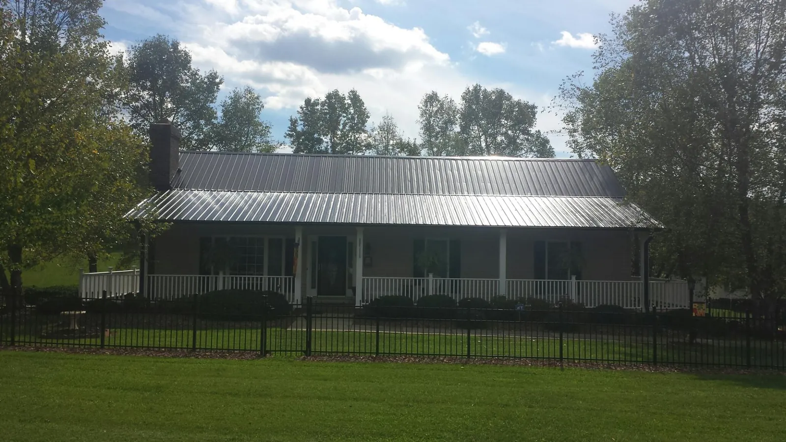 Gray metal roof on a brick ranch with a full width front porch — Gutter Guard Installation work by our crew in Kirkersville