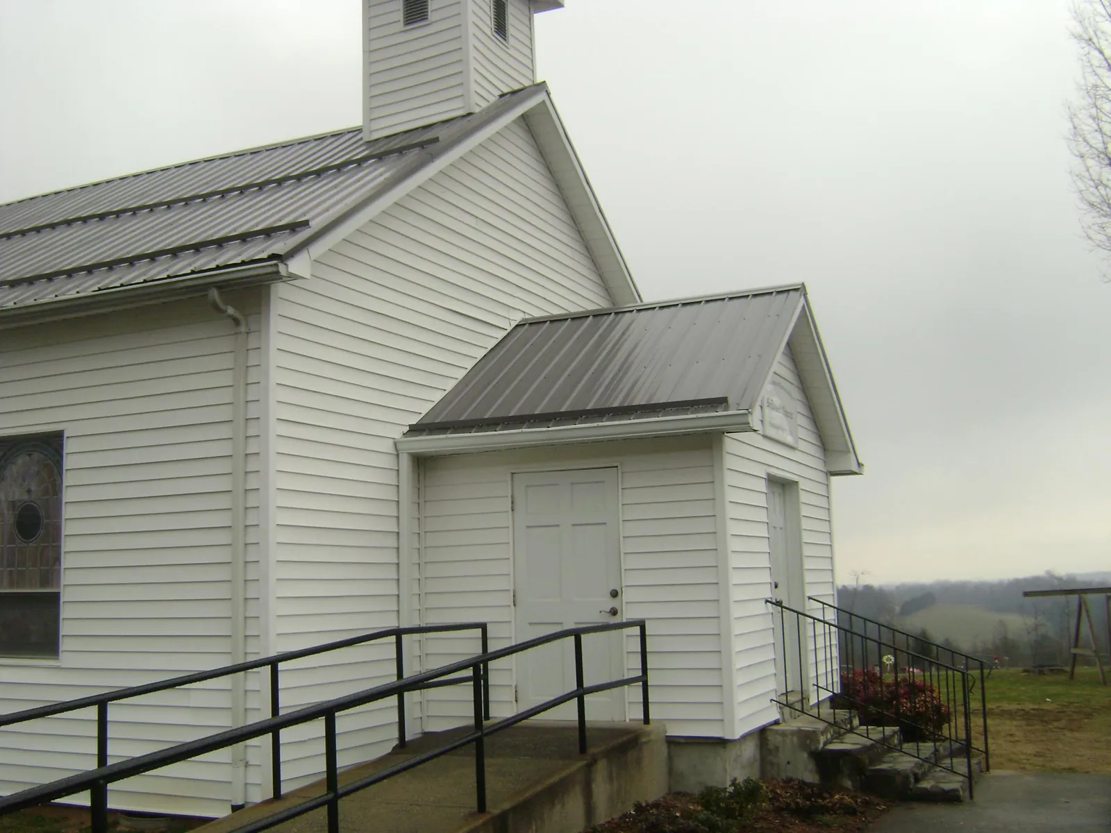 Gray metal roof on a white clapboard church with a steeple in Kirkersville