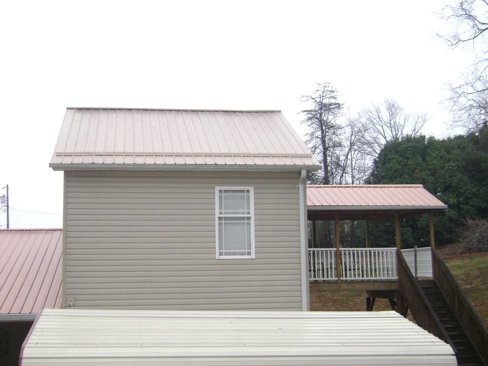 Tan metal roofs on a two story addition and attached porch, from a Roof Replacement job in Kirkersville