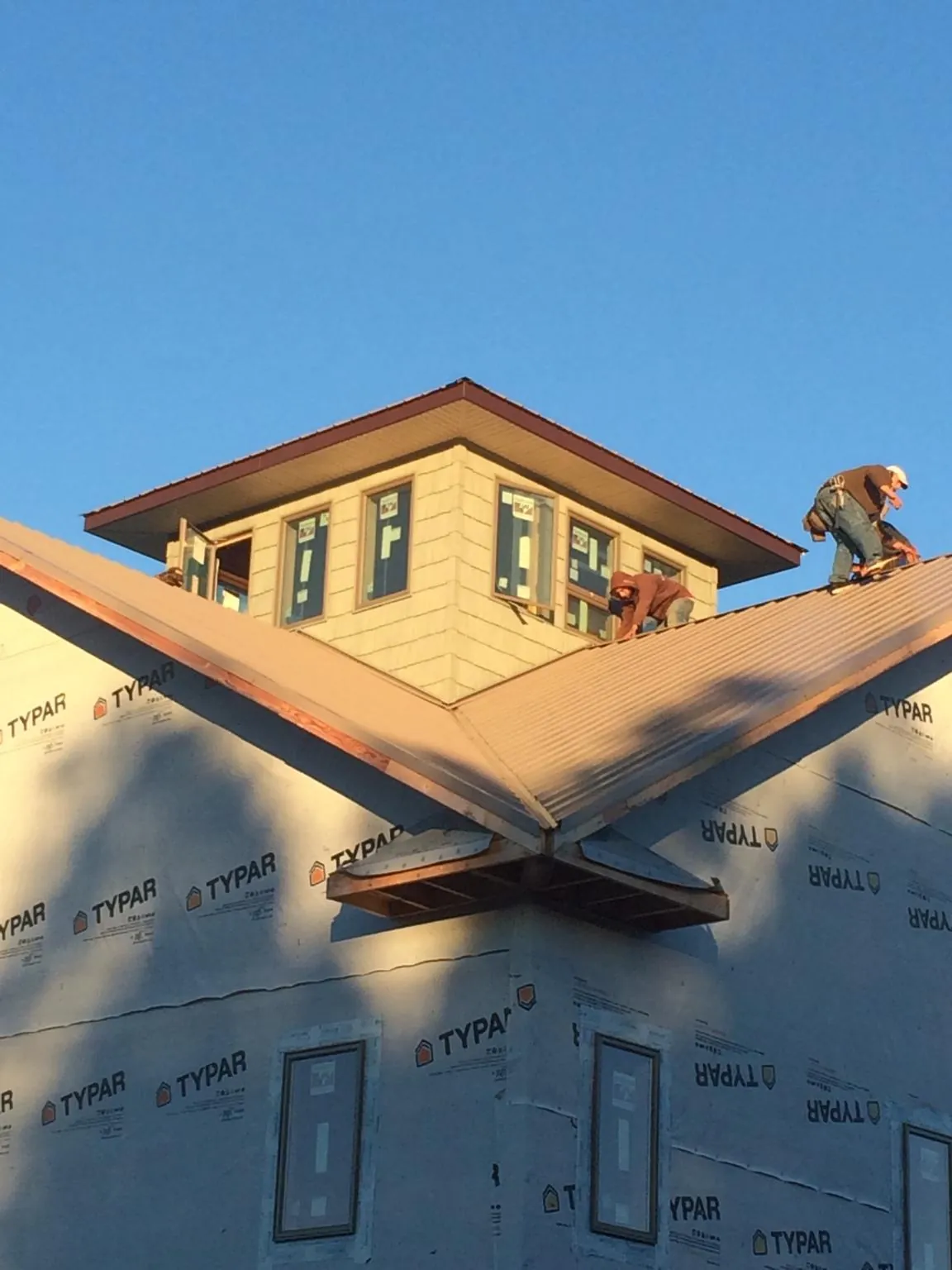 Roofers working around a rooftop cupola on a new metal roof at sunset — Roof Waterproofing in Kirkersville by Roofing Brothers